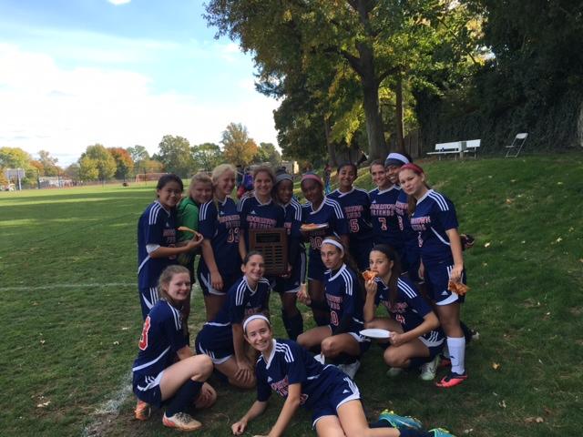 The team celebrates its victory around the tournament plaque