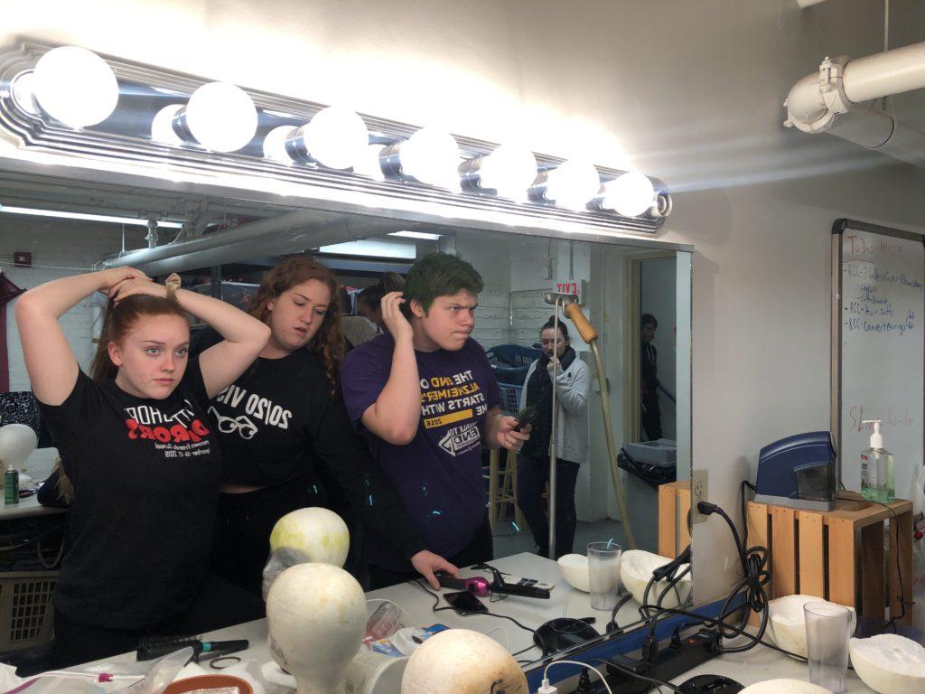 Students prepare for the performance with help from the costuming staff.