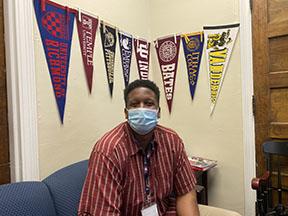 Photo by Esha Patel. Mr.Vassall poses with just a few of the college flags around his office.