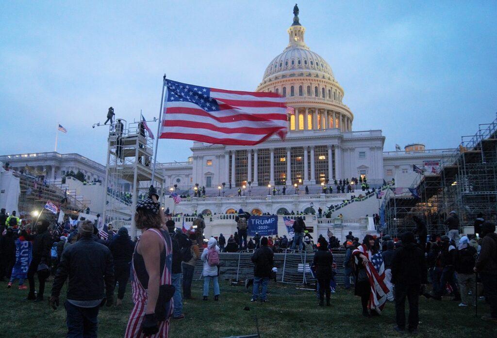 Rioters surround the Capitol with various flags as the sun begins to set in Washington DC on January 6, 2021