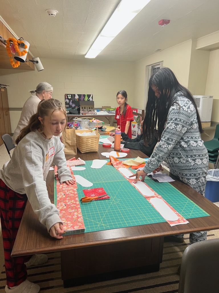 A group of eighth graders work with Van Tijn to cut fabric. Photo provided by PASHI Moorestown.
