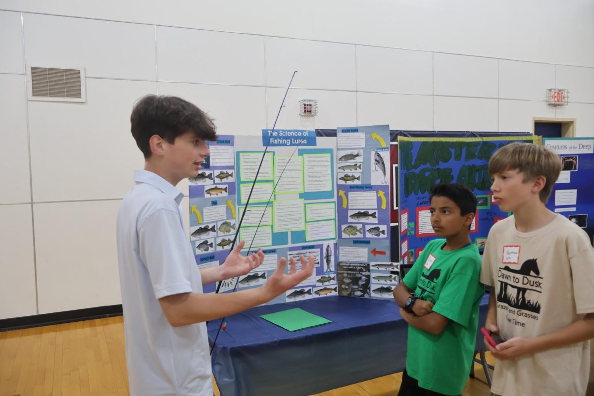 Noah Olsen '31 presents his project about the science behind fishing lures to two students.
